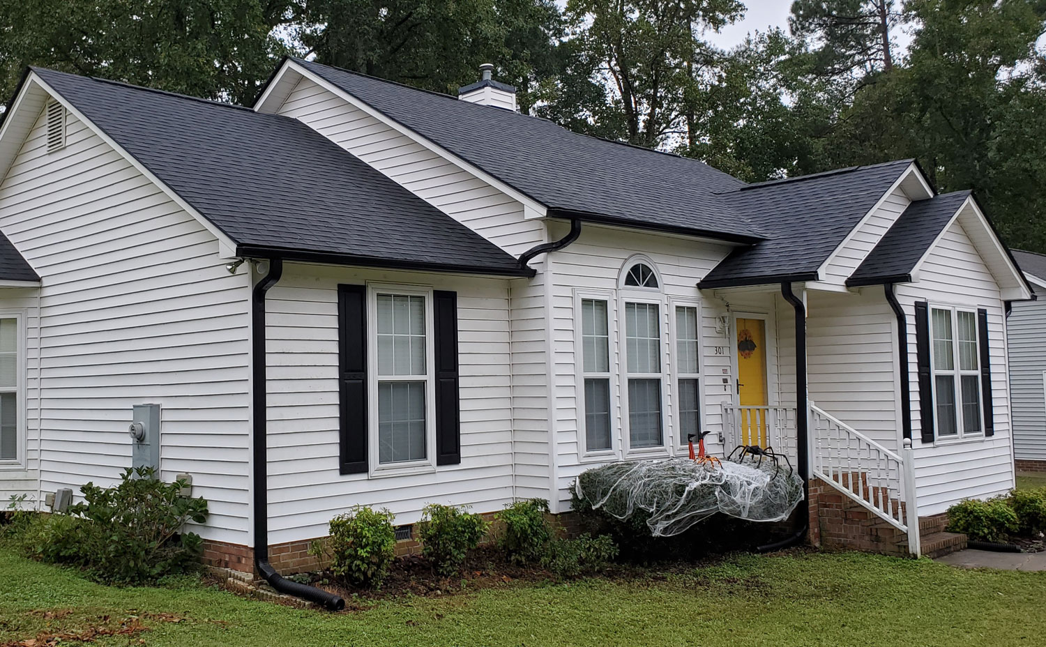White rambler-style house with black gutters and downspouts